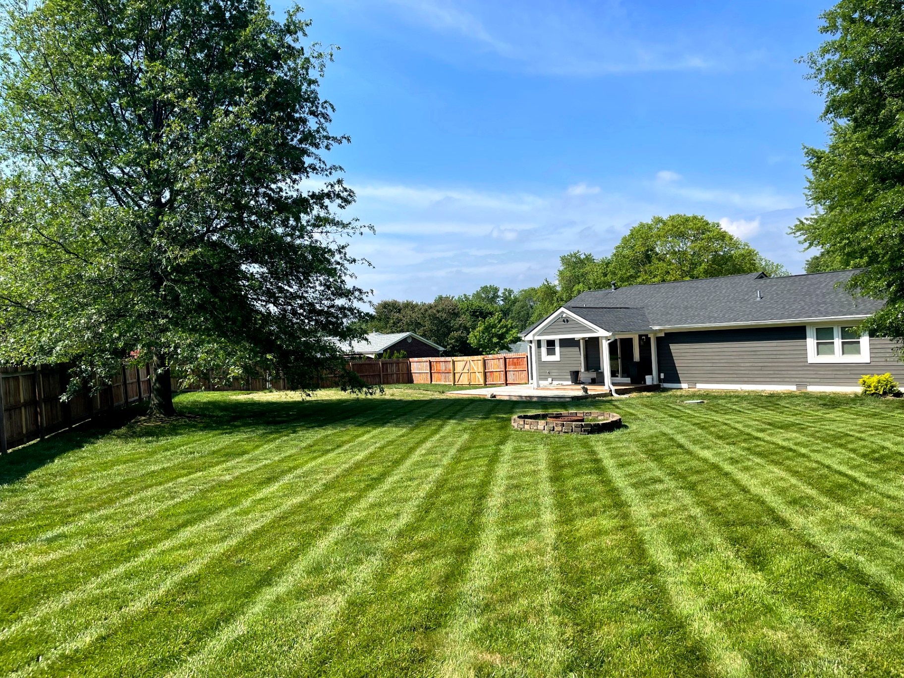 Green striped backyard lawn around a stone fire pit